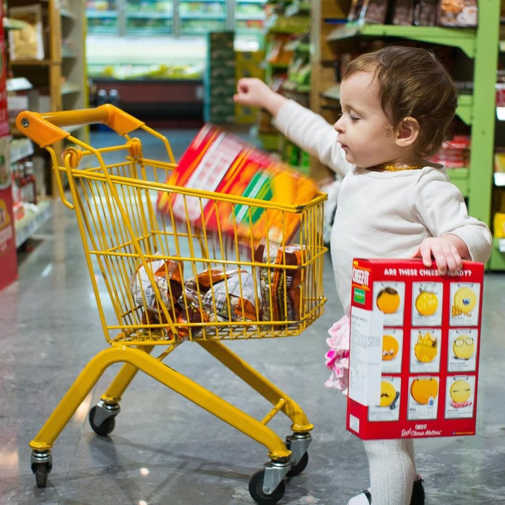 Una bimba fa spesa con il suo piccolo carrello